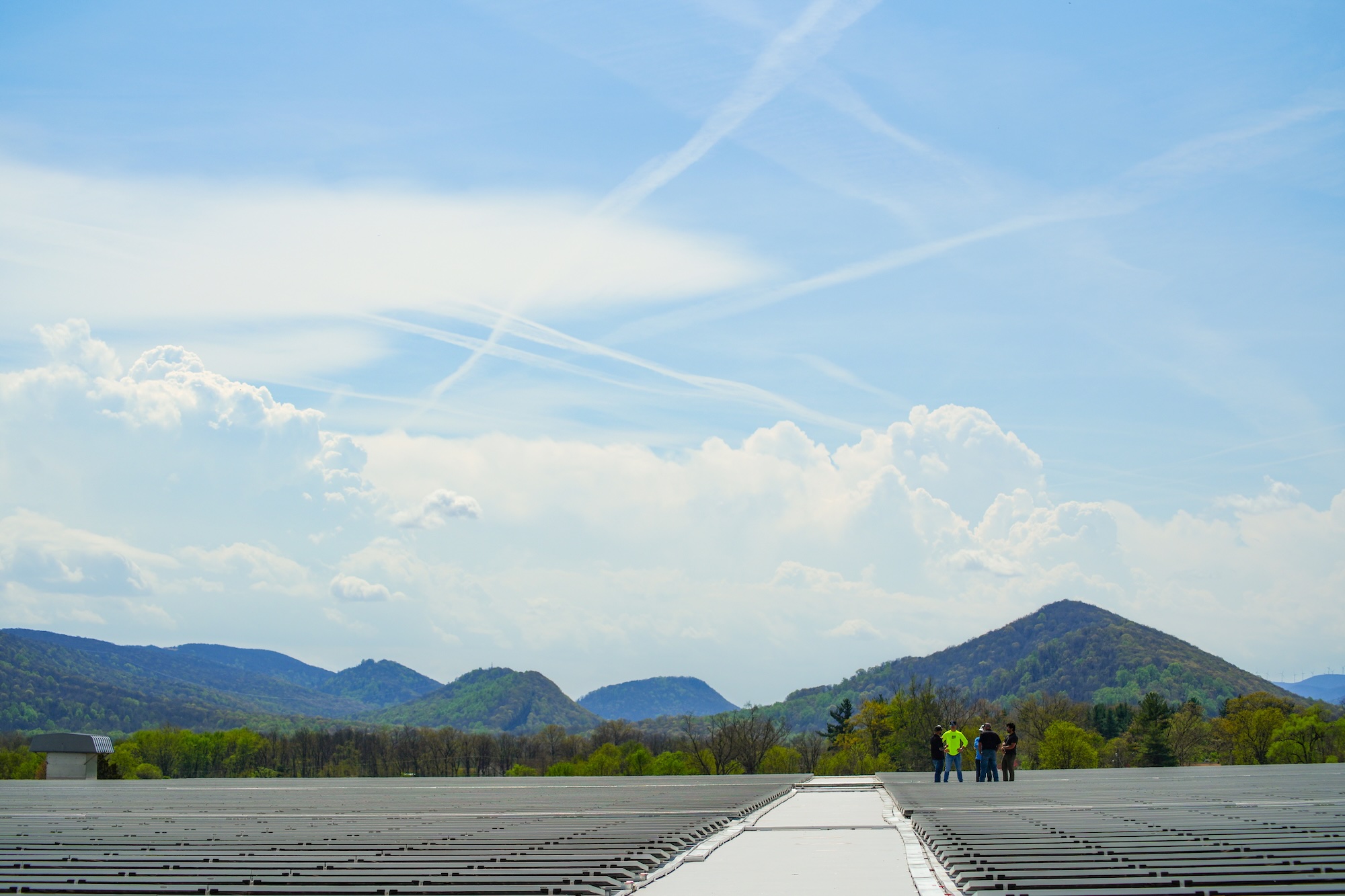 guys standing in front of mountains with blue skies talking about solar energy
